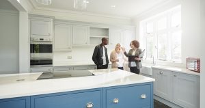 saleswoman or estate agent shows a couple around a home with new kitchen