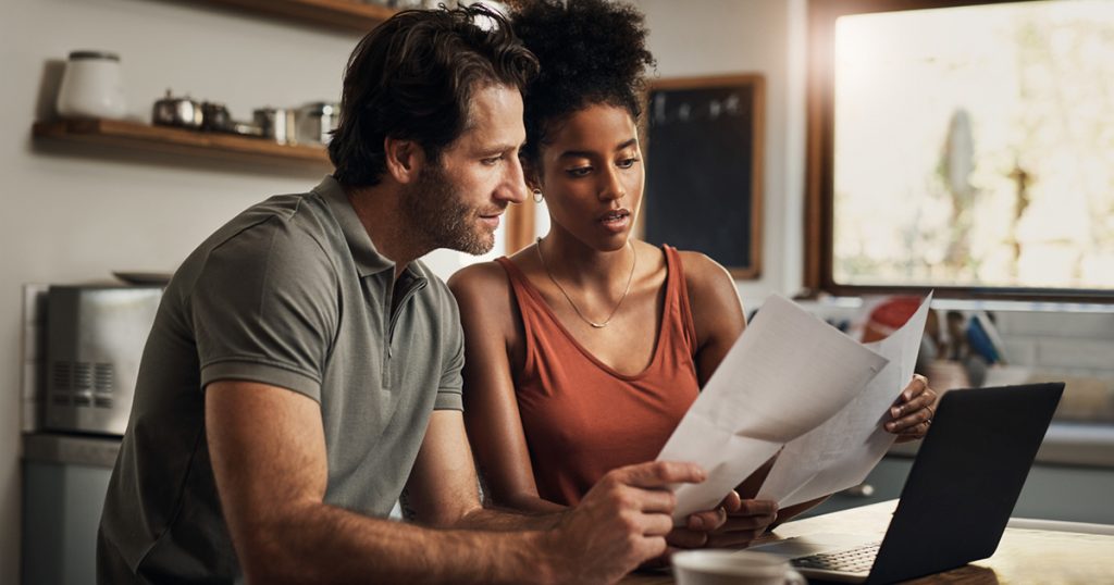 affectionate young couple going through paperwork while doing their budget at home